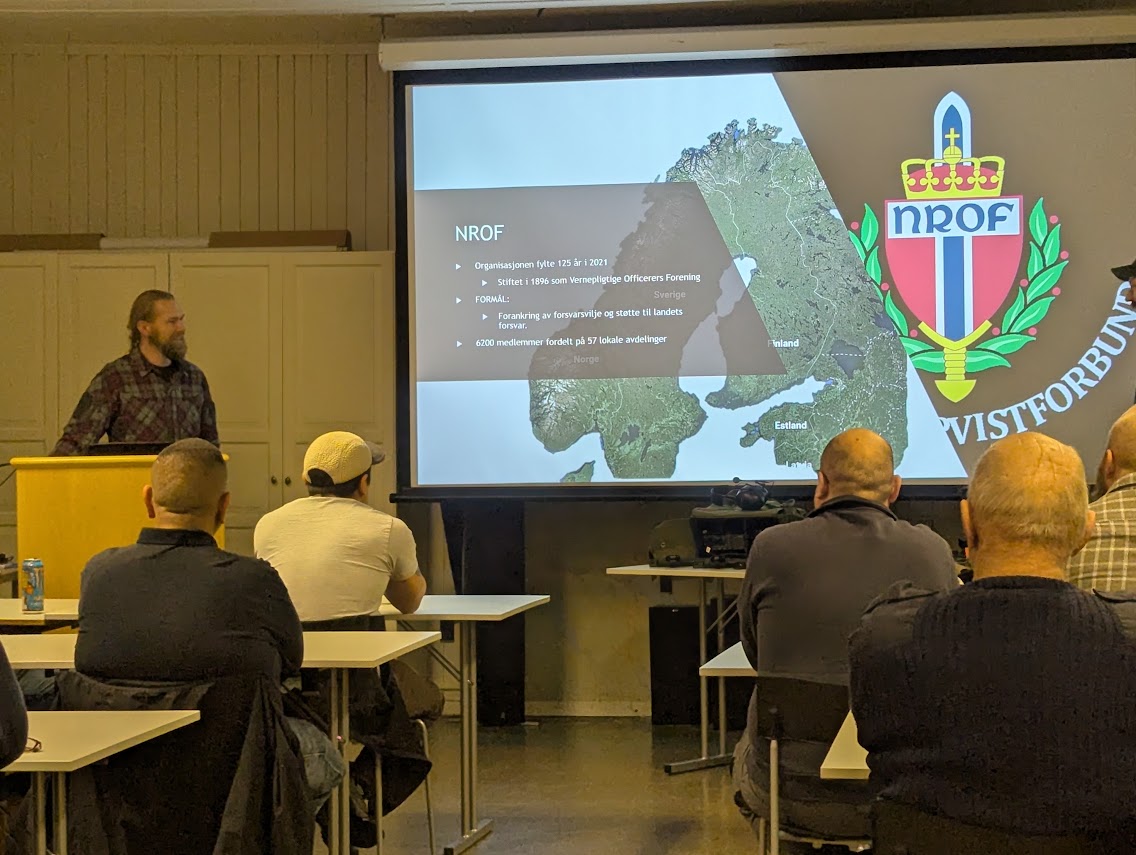 Foredrag om NROF på medlemsmøte, med kart og forbundets emblem på lerretet