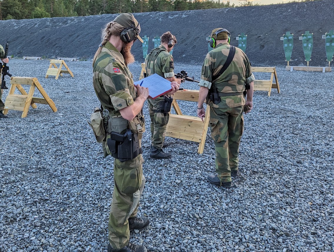 Skyttere med rifle på skytebanen, en fører skyteliste